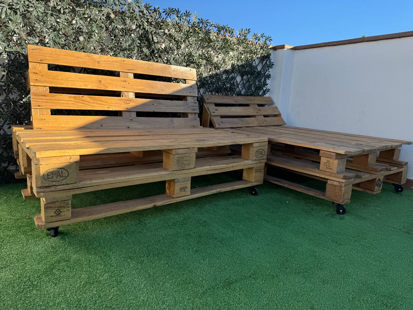 Conjunto de sofá y tumbona fabricados con madera de palé recuperada y ruedas
